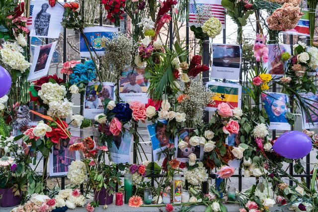 Flowers and photos of the Tremont Fire victims are pinned to a fence outside of the Twin Parks North West building in the Bronx.